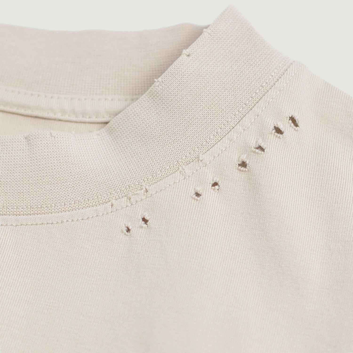 Close-up of distressed elements on the oversized tee, highlighting the worn cuffs, collar, and hem with a washed effect and tonal gradient, adding an edgy, vintage-inspired touch.